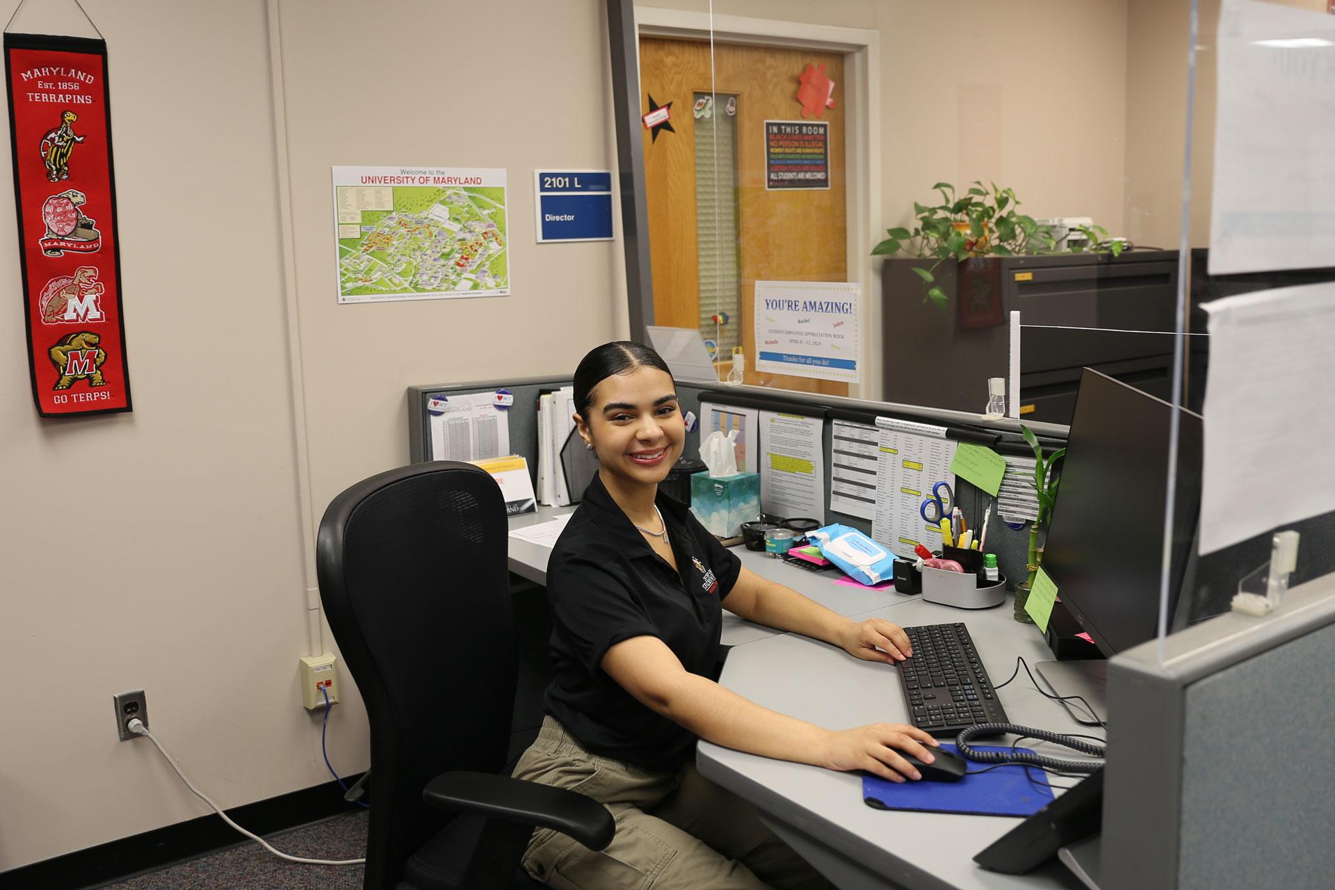 Office assistant at a desk in the director's suite in Annapolis Hall