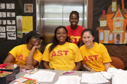four AST volunteers behind a welcome table in the residence hall