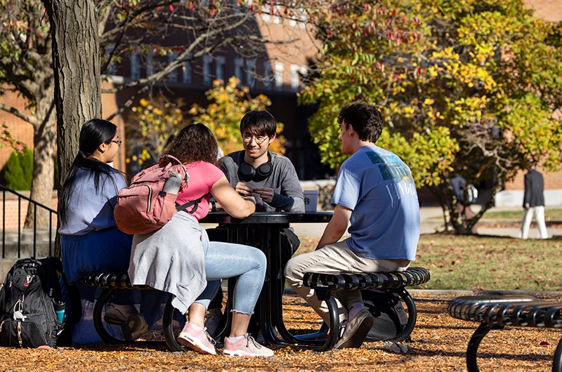 Students sitting at table outside Hornbake Plaza on a fall day