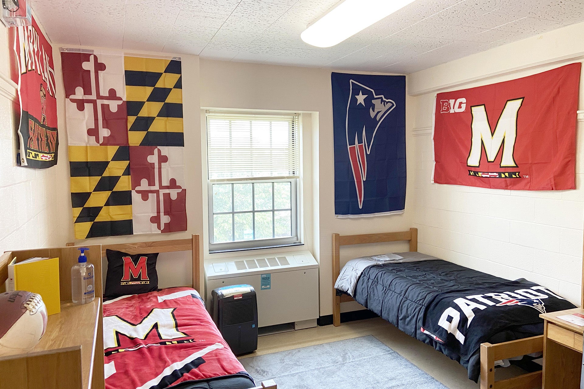 Traditional double room with two twin beds, desks, and Maryland flags on walls.
