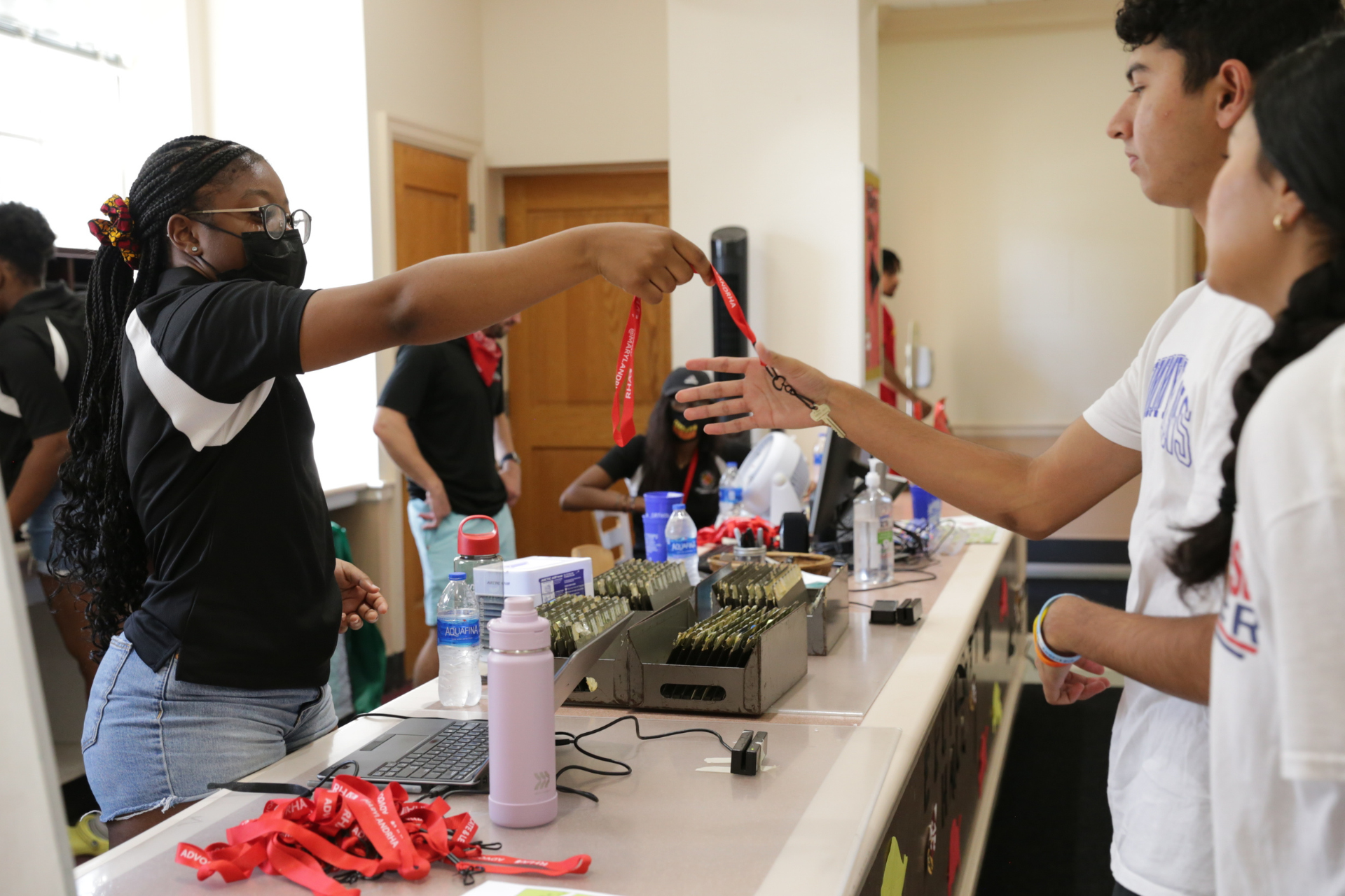 student reaching across the counter to grab their keys from the service desk attendant