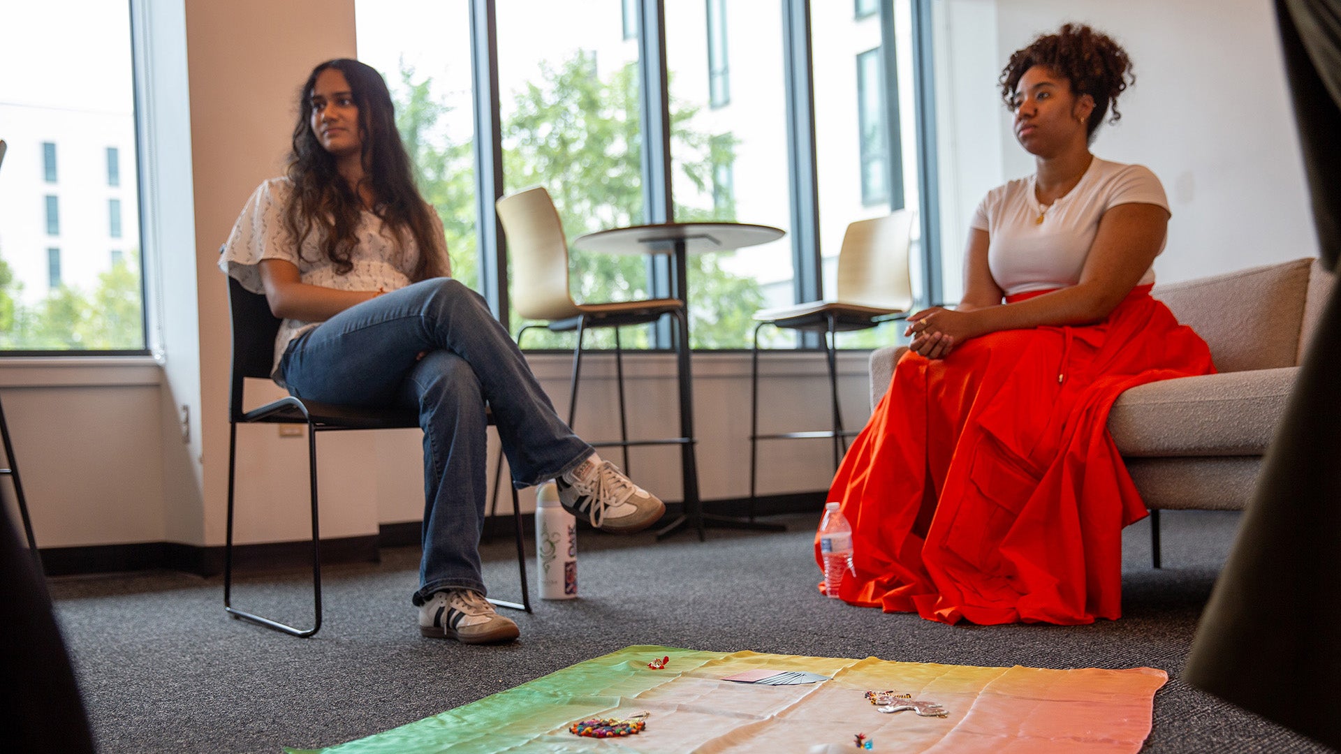 Two people sitting in a restorative circle with a centerpiece cloth on the floor at the center.