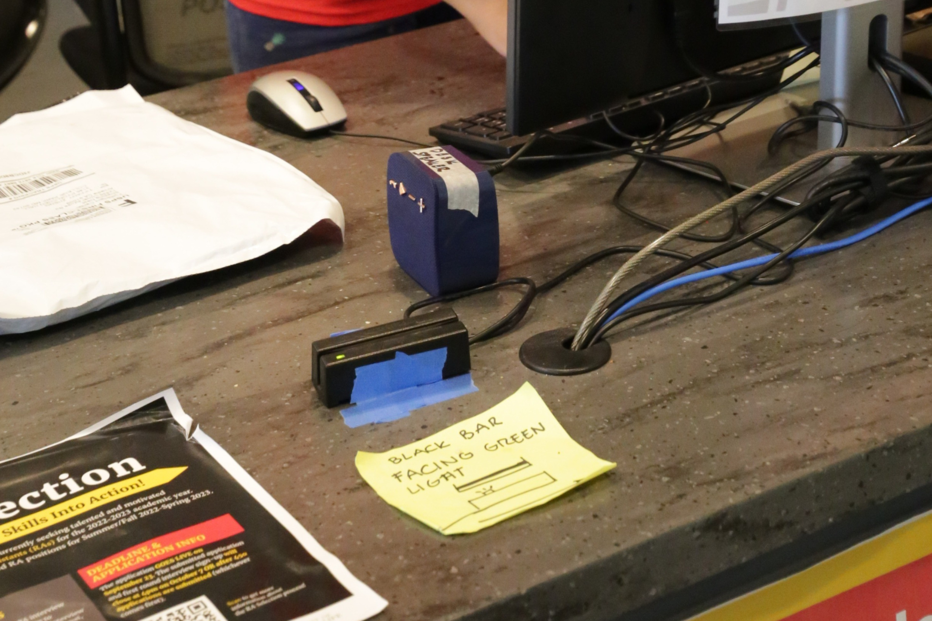 card swipe device on service desk with handwritten note that provides instructions