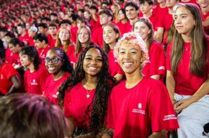 Crowd of students in red "Department of Resident Life" shirts smiling at the Big Show event during Fall Welcome.