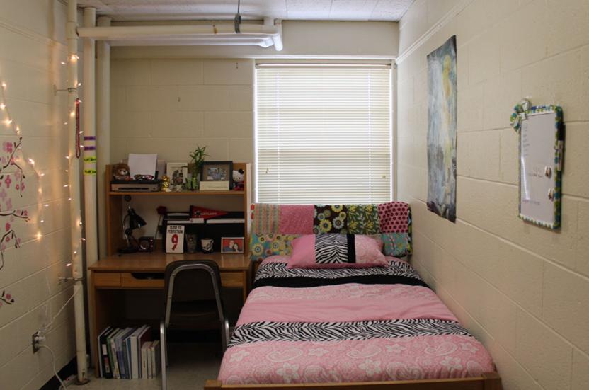 single room with a bed, pink duvet cover and desk