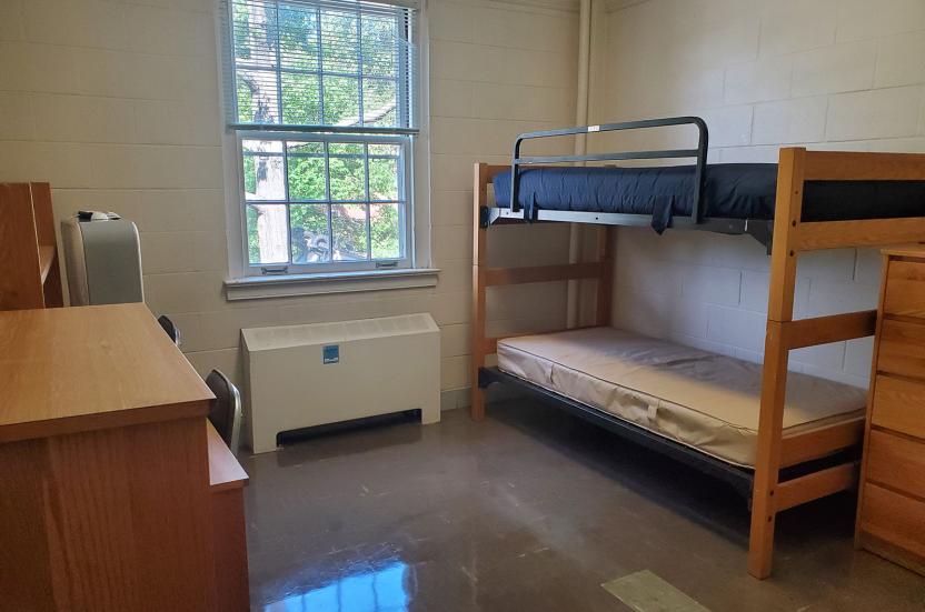 a wooden bunk bed, a desk with chairs, and a window.