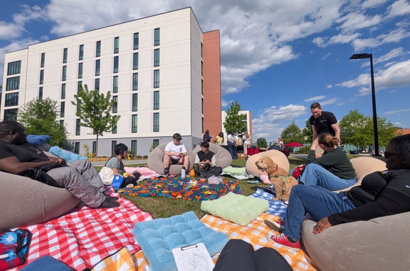 Volunteers sitting on bean bags chairs and engaging in conversations in a restorative circle outdoors in Heritage Plaza.