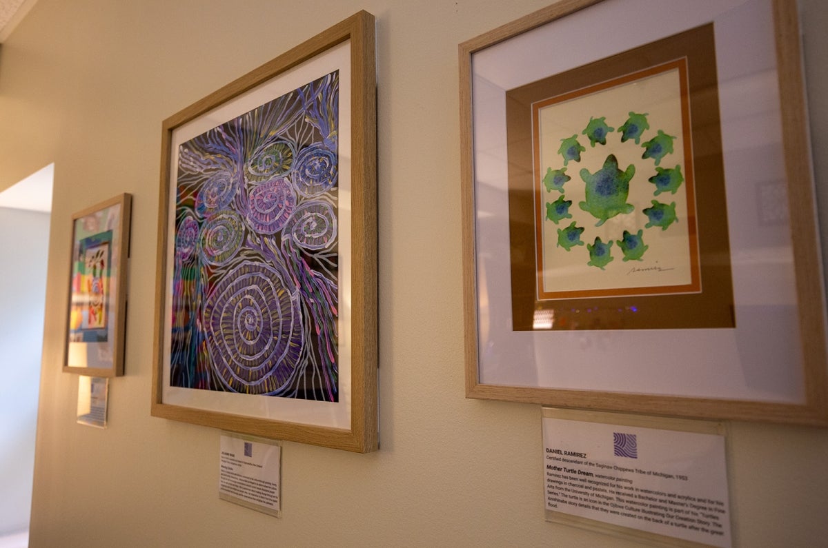 three pieces of framed artwork by indigenous artists are displayed on a wall in the Restorative Circle Center. 