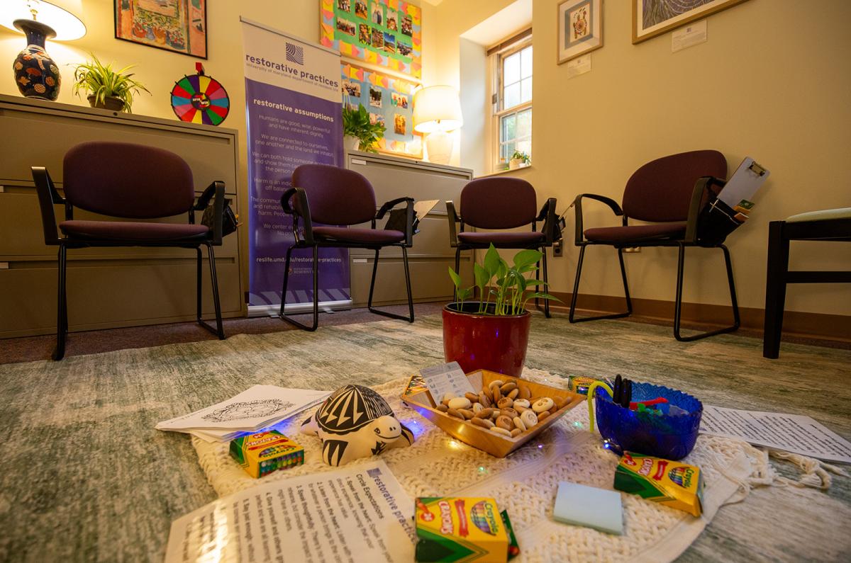 a restorative circle centerpiece, comprised of a plant, crayons, expectation handouts and wood tokens, providing a shared focal point for participants.