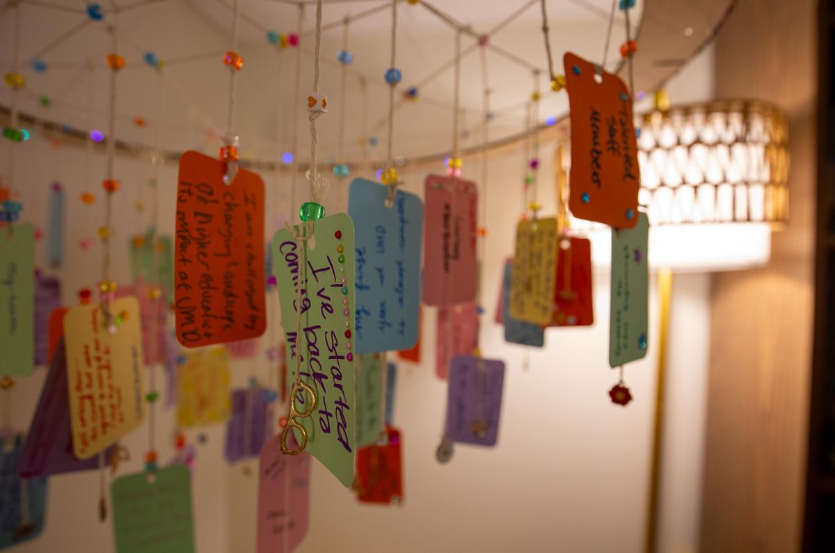 a hanging mobile of papers with quotes and affirmations attached to strings.