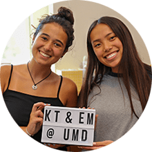 two roommate holding up a sign that says KT and EM at UMD