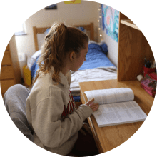 student reading book at desk in residence hall room