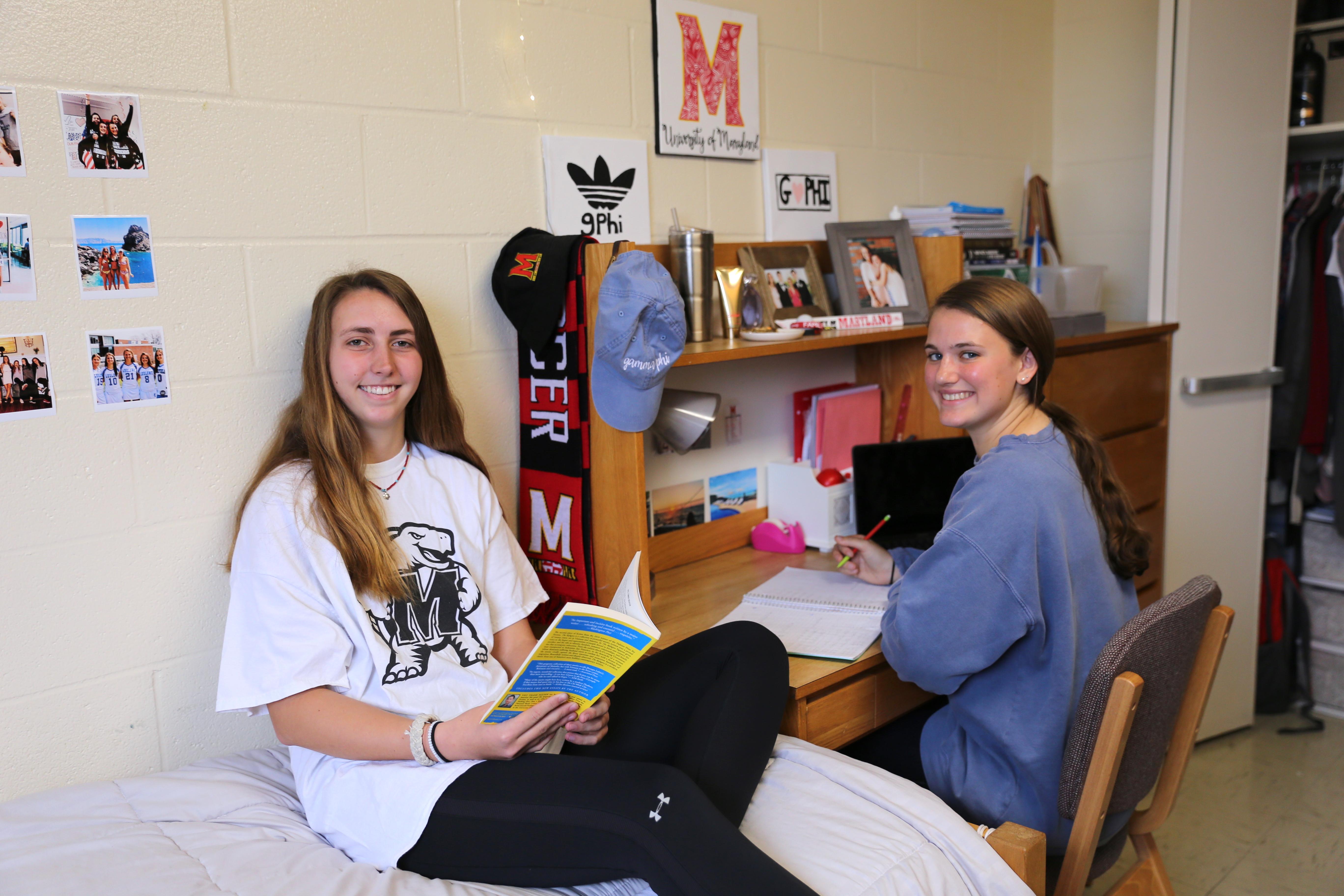 two female roommates smiling at the camera in their dorm room