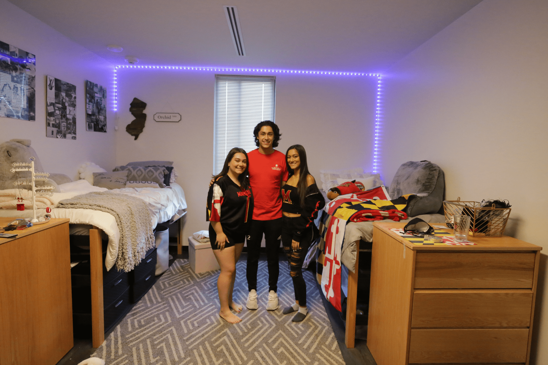 three students posing inside a dorm room