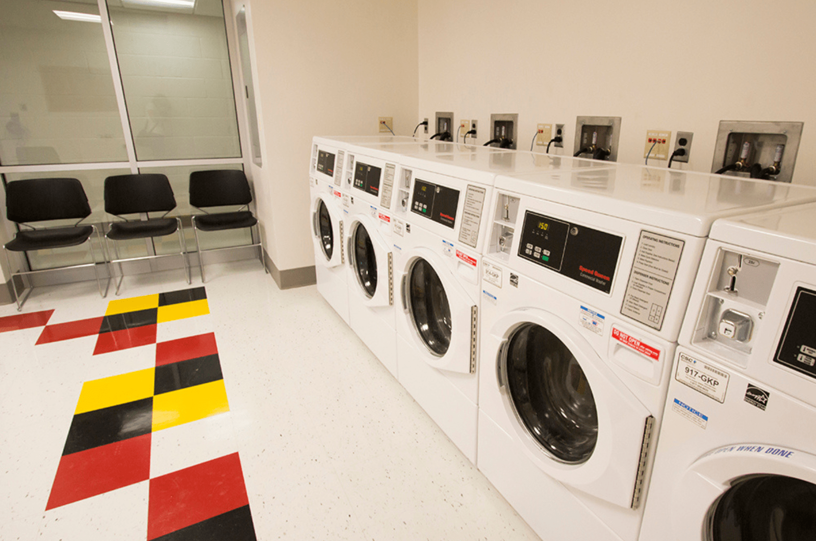 laundry room with machines lined up side by side and waiting area seating