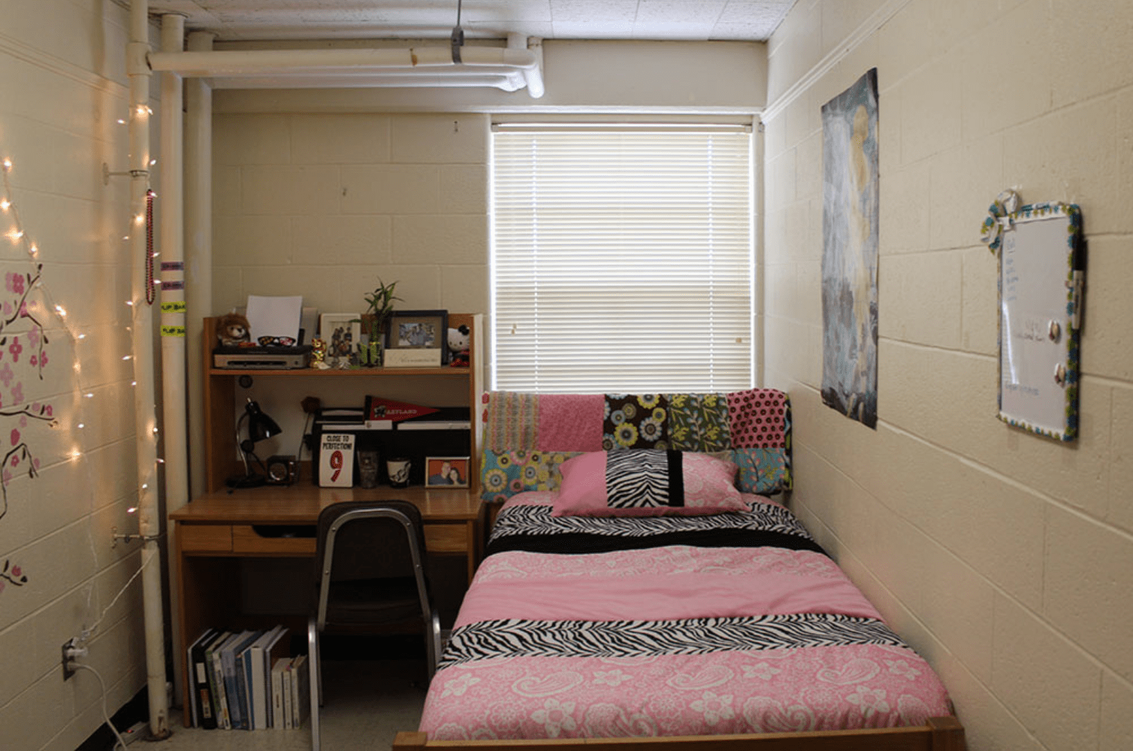single room with a bed, pink duvet cover and desk
