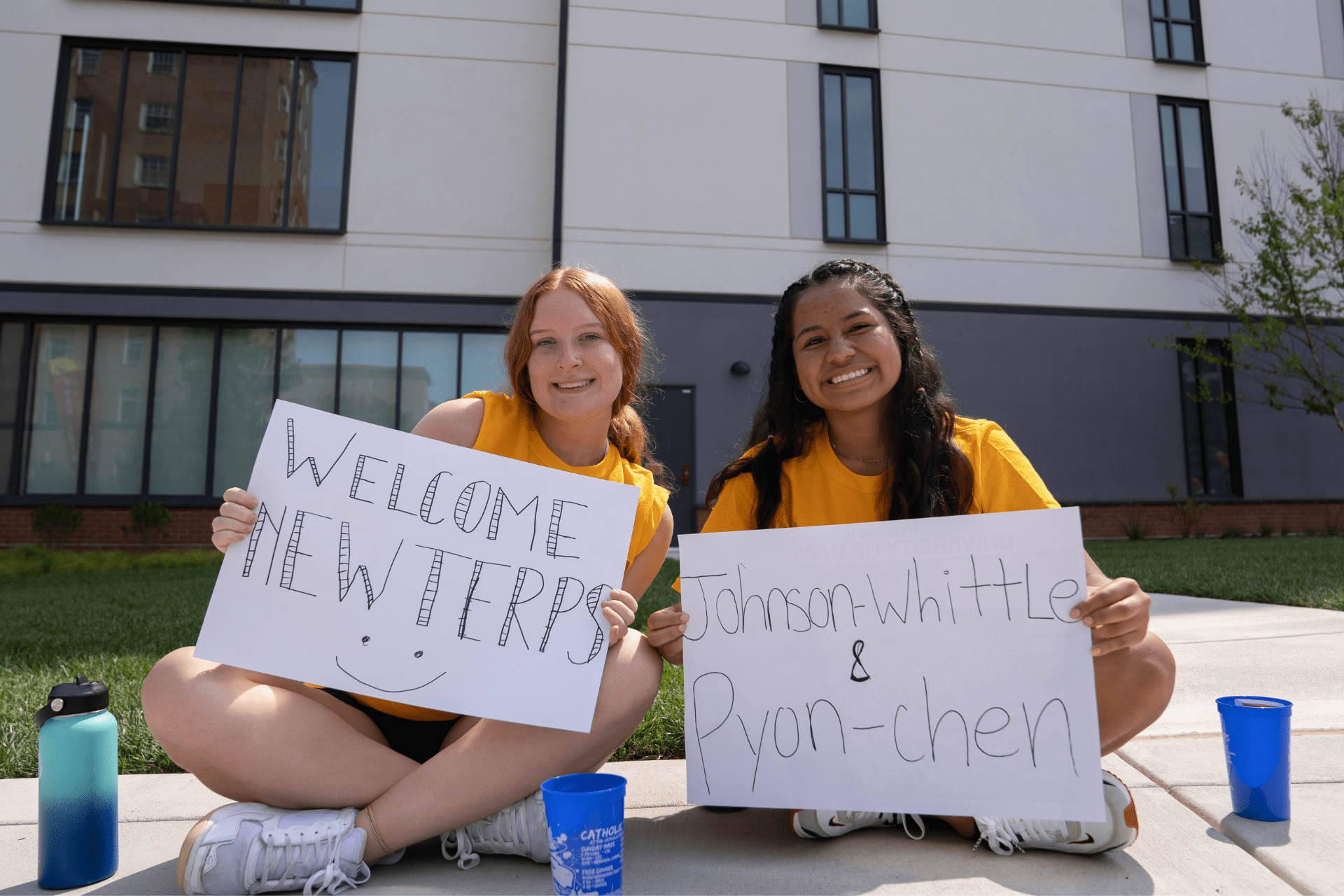 two students with handmade signs welcoming new Terps during move-in