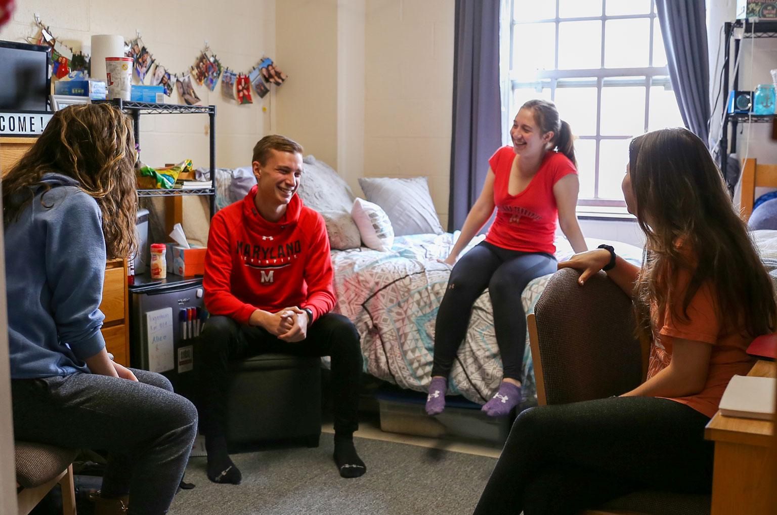 four students hanging out in residence hall room