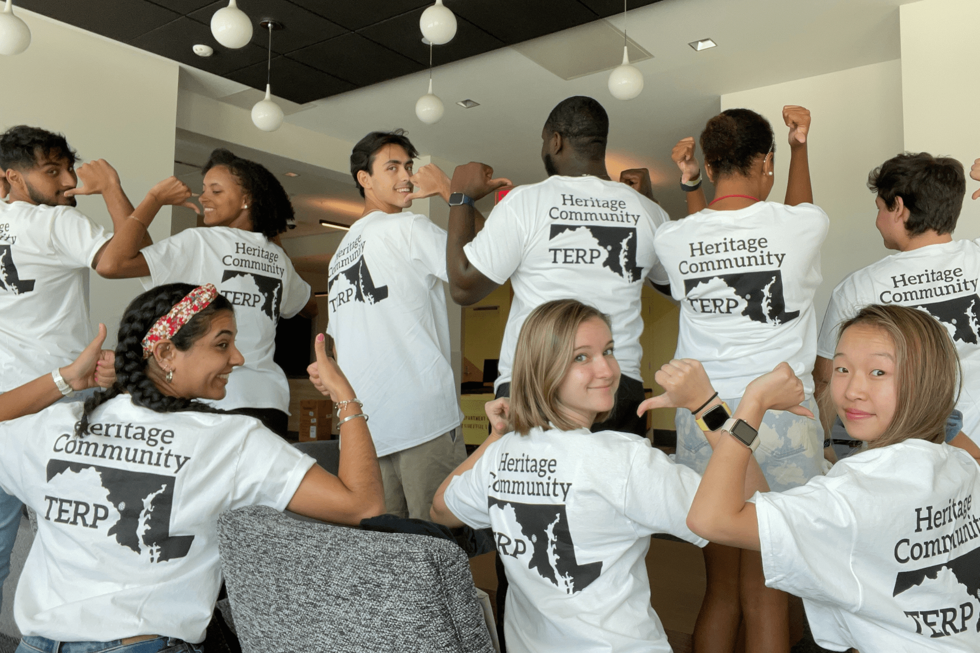 students pointing to the backs of their heritage community shirts
