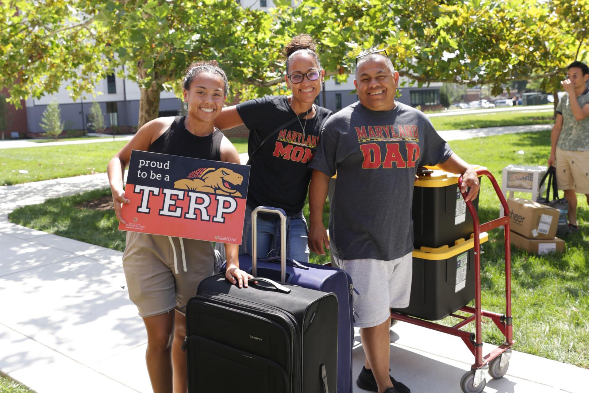 student with parents holding proud terp sign during move-in