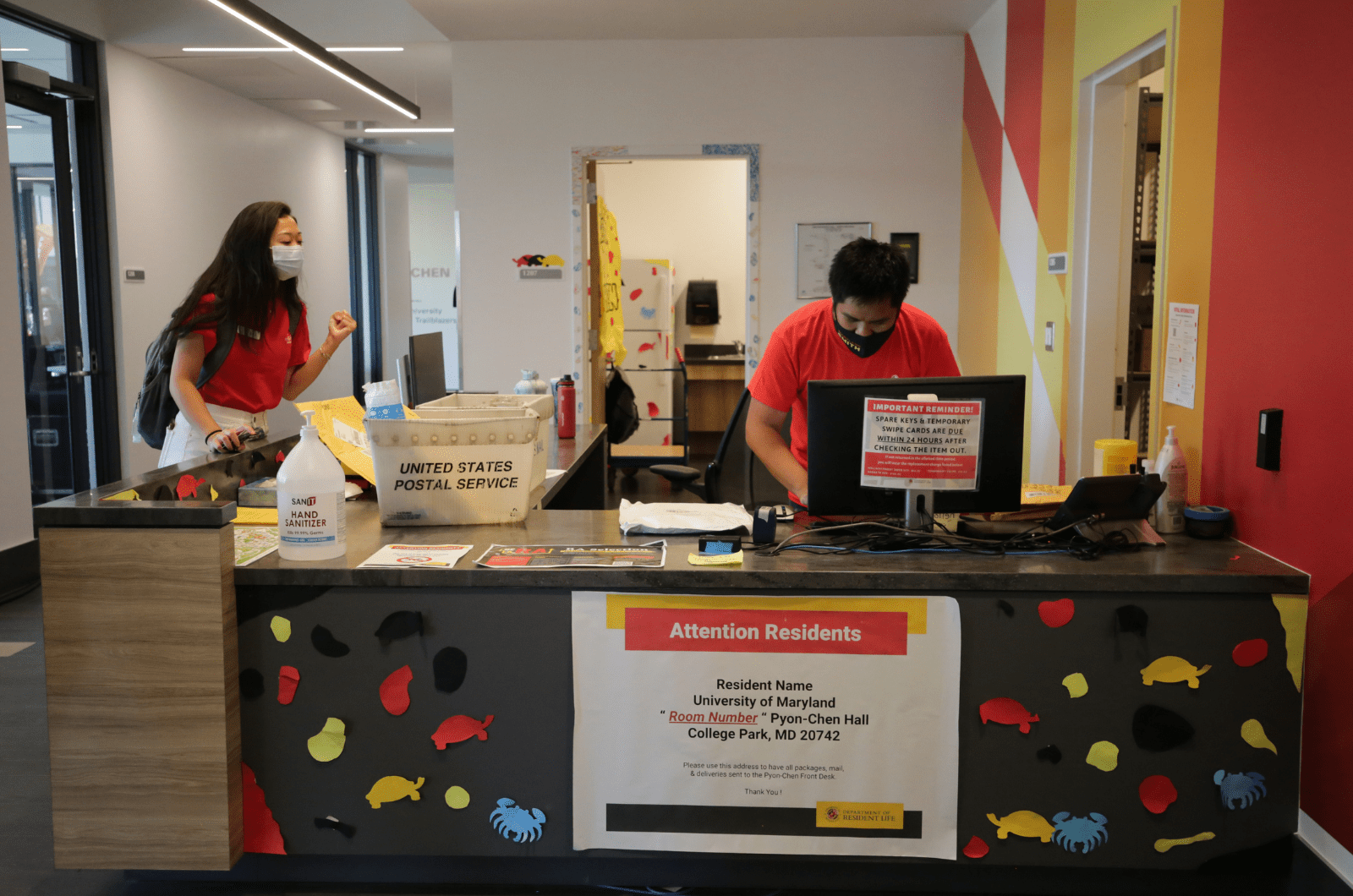 student staff looking up something on a computer for a resident who is waiting by the service desk