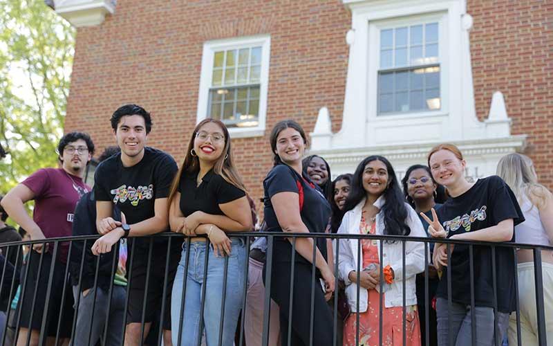 students posing over railing outside residence hall building 