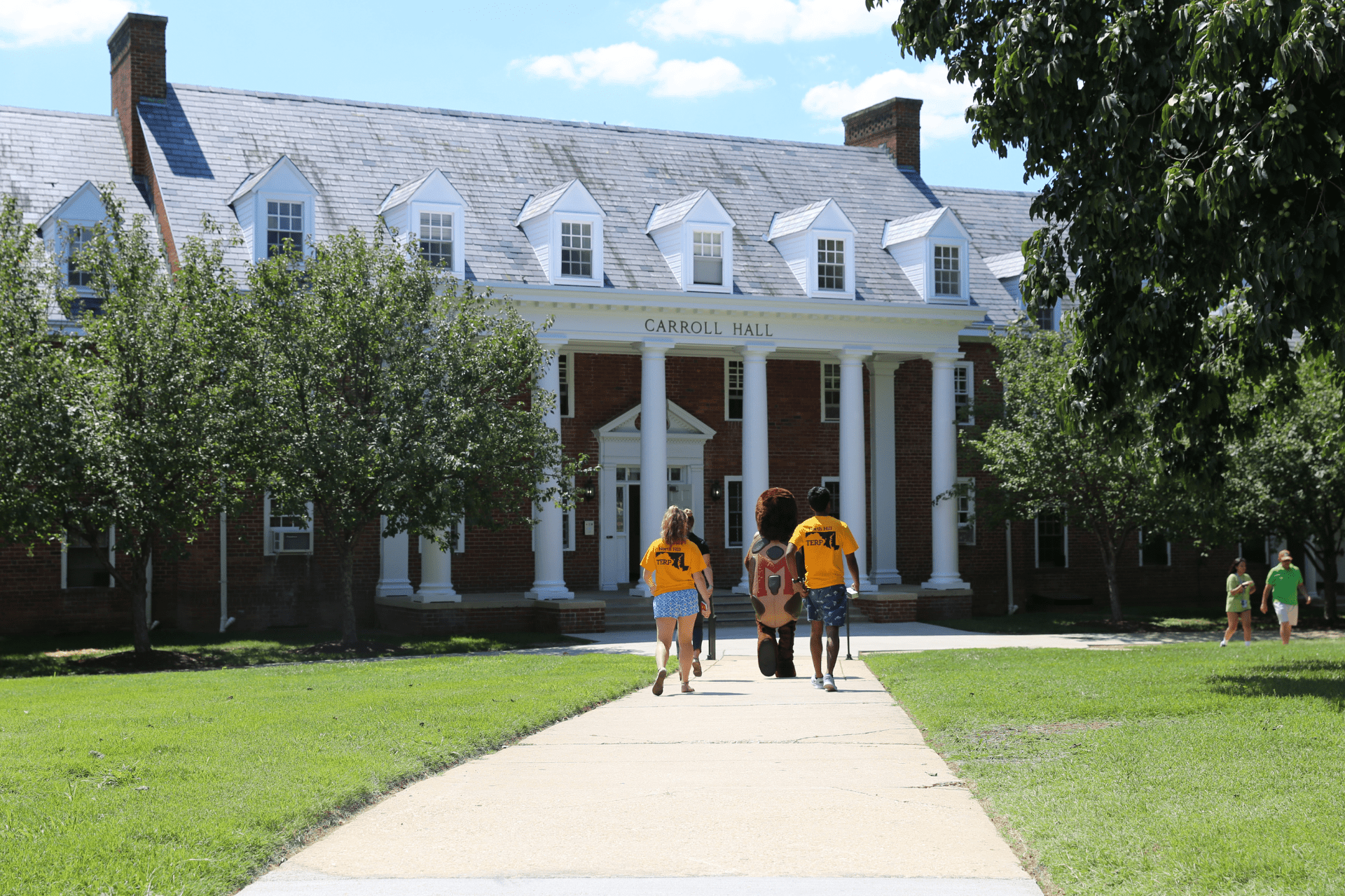 students and testudo mascot walking outside Carroll Hall