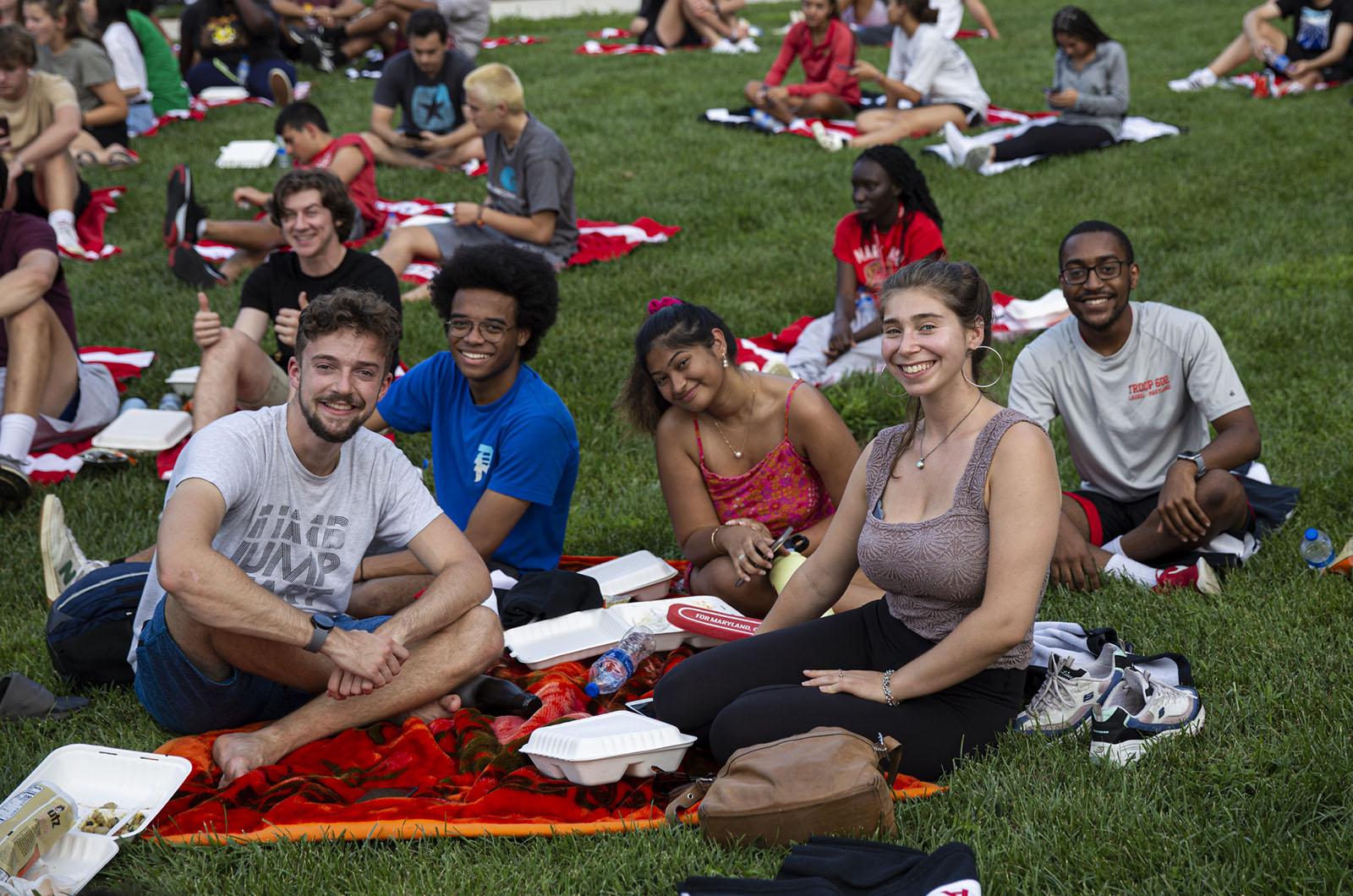 five students sitting on a towel on McKeldin Mall during the new student welcome event