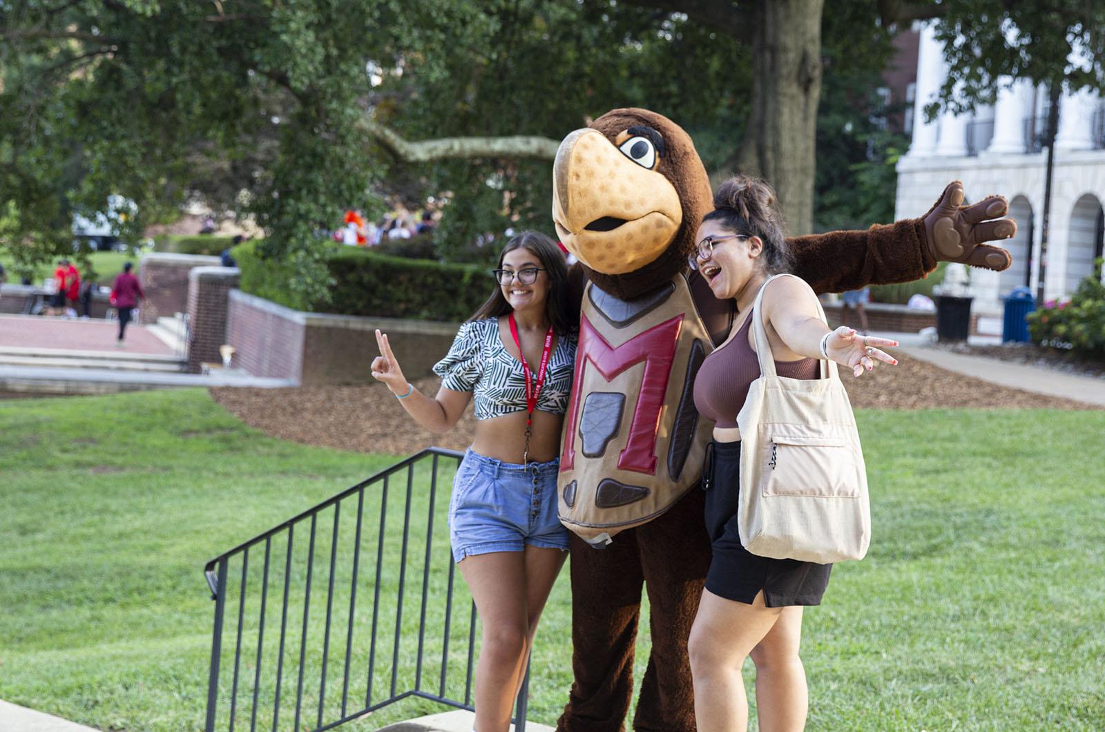 two students hugging the Testudo mascot during the new student welcome event on McKeldin Mall