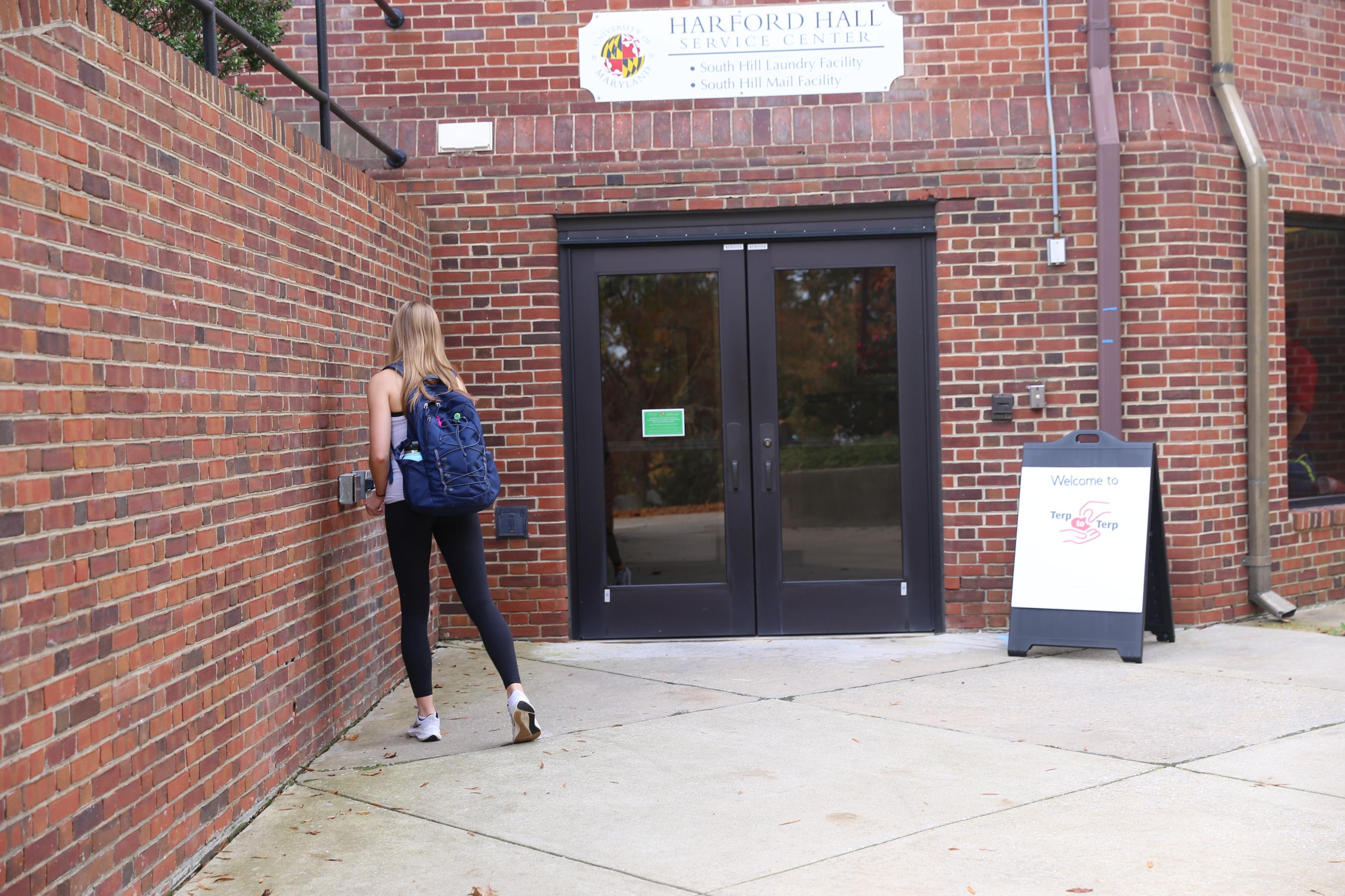 student swiping key to access harford hall through the service entrance