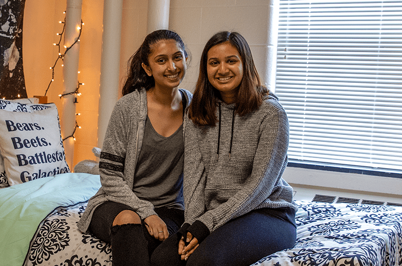 two roommates sitting on bed in residence hall room