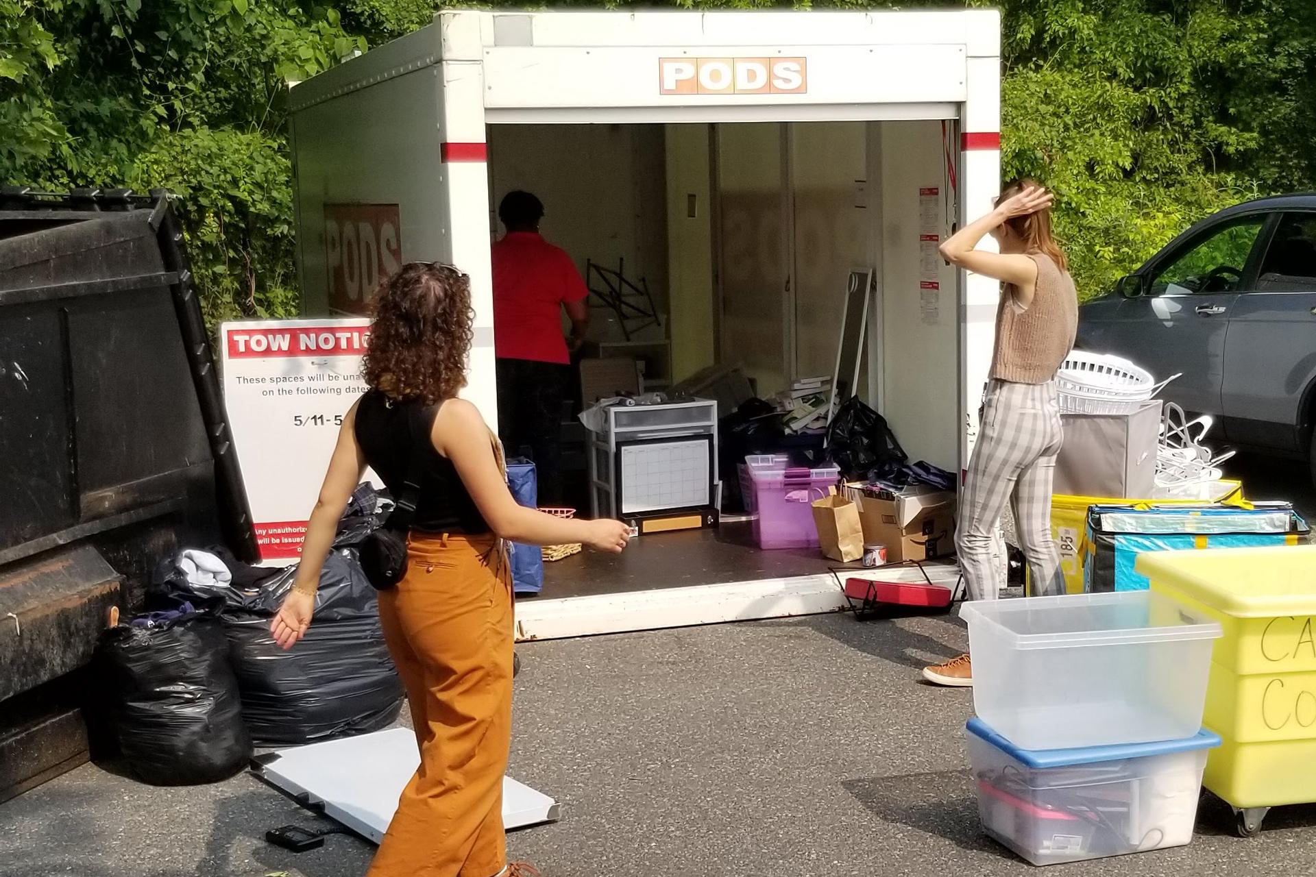 three volunteers helping sort donations in a pod outside