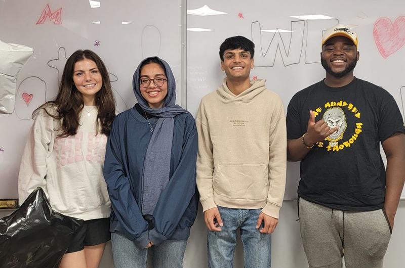 four creative services students smiling in front of a whiteboard