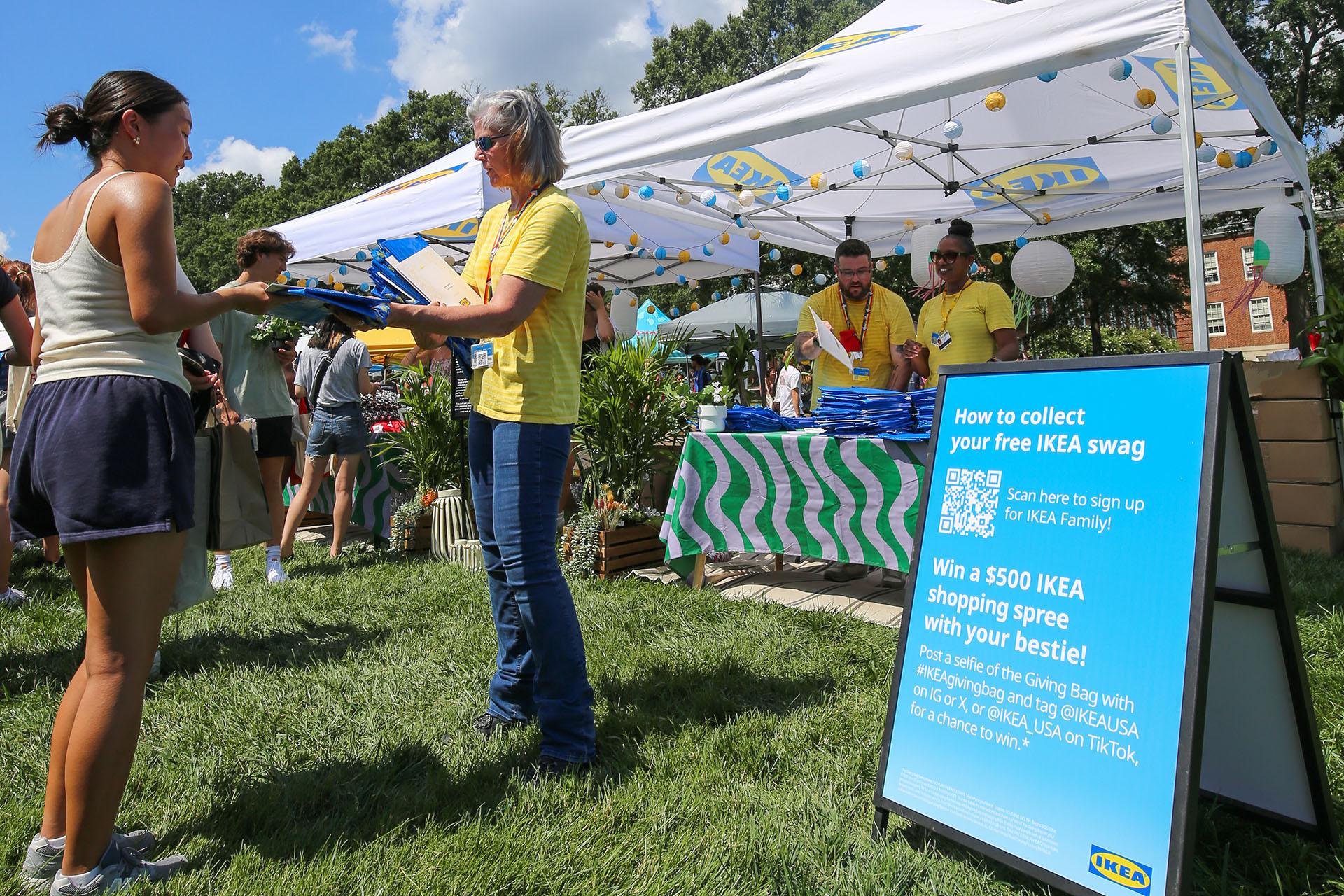 ikea employee handing out blue shopping bags to students during Fall Welcome