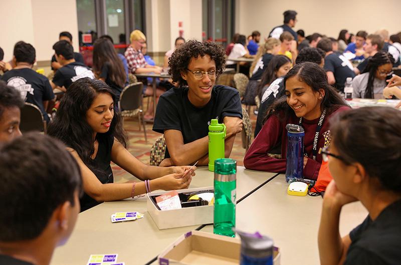 Group of students playing card game in a residence hall multipurpose room during Fall Welcome