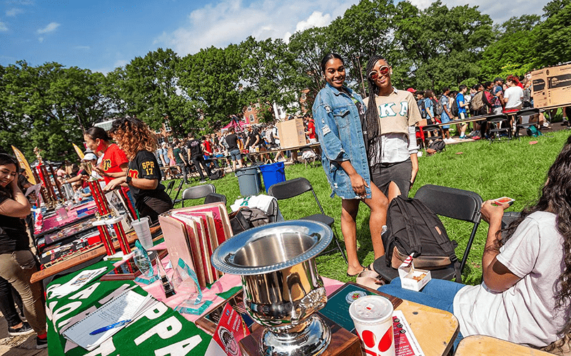 two sorority students posing behind a table during the first look fair.