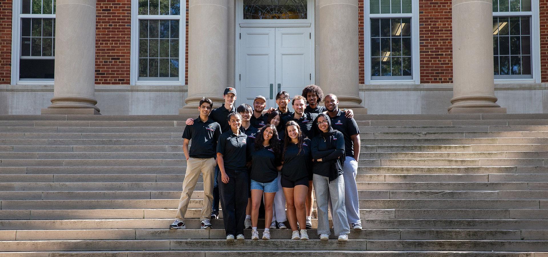 group of resident assistants posing on the steps of a campus building.