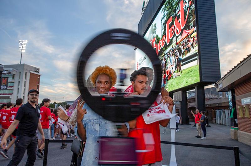 Two students pose at a "360-degree" photo booth during the Big Show event at the football stadium.