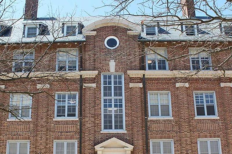 Exterior of Calvert Hall, a brick residence hall with a central arched roofline and white windows.