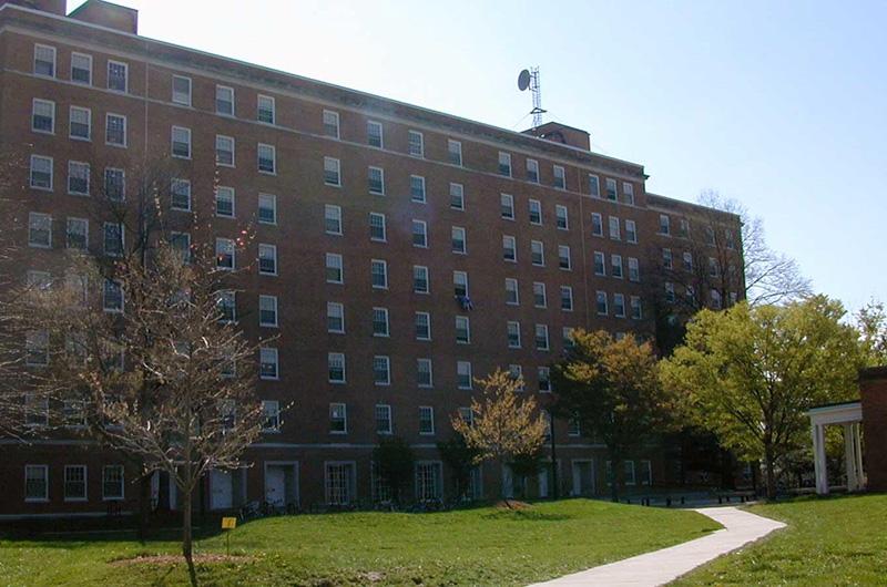 Exterior of large brick Centreville Hall next to a grassy lawn and winding sidewalk.