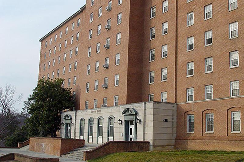 Exterior of brick Denton Hall with gray stone entryways and steps leading to the entrance.