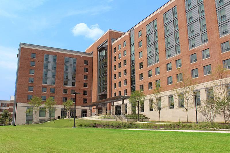 Exterior of Prince Frederick Hall, a modern, multi-story brick residence hall with large windows and a lawn.
