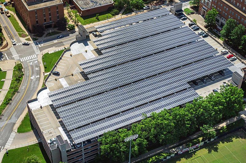 Aerial view of a multi-level campus parking garage covered with rows of solar panels.
