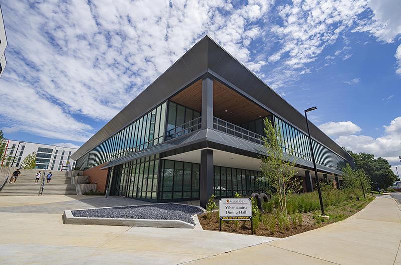 Modern, two-story glass and brick Yahentamitsi Dining Hall building under a blue sky.