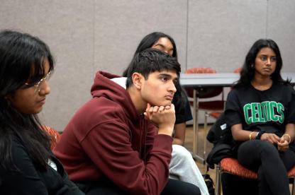 Four students seated indoors, listening attentively during a group discussion.
