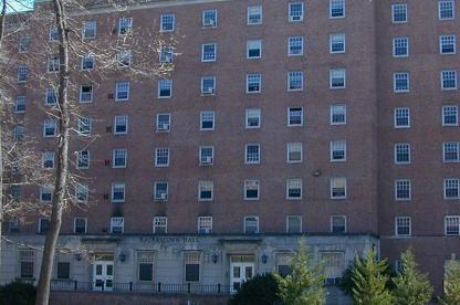 Exterior of brick Hagerstown Hall with stone entryways and small green trees in the foreground.